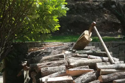 a pile of logs with a stone wall with a shovel at Alivi Di A Restonica in Corte