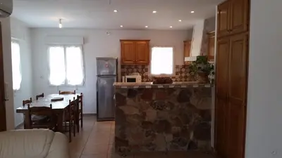 a kitchen with a stone counter and a dining room at Villa de charme au bord des piscines naturelles in Ventiseri