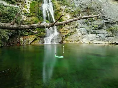 a waterfall and a lake with a green bucket in the water at Villa de charme au bord des piscines naturelles in Ventiseri
