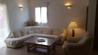 a living room with a white couch and a table at Villa de charme au bord des piscines naturelles in Ventiseri