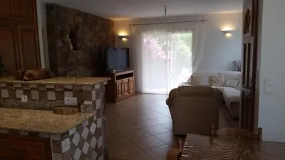 a living room with a couch and a television at Villa de charme au bord des piscines naturelles in Ventiseri