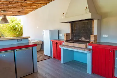 a kitchen with red cabinets and a brick oven at Villa Lisa Porto-Vecchio in Porto-Vecchio