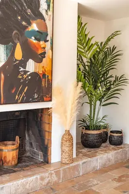 a living room with a painting and plants on a fireplace at Villa Lisa Porto-Vecchio in Porto-Vecchio