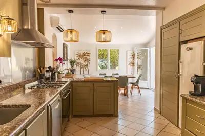 a kitchen with green cabinets and a dining room at Villa Lisa Porto-Vecchio in Porto-Vecchio
