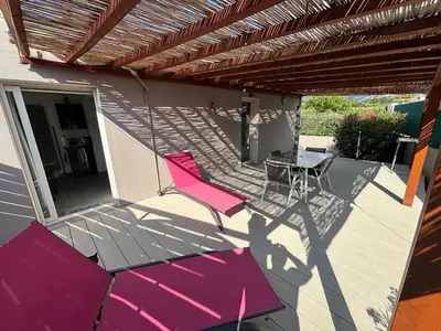 a patio with a pink umbrella and a table and chairs at villa Morgane in Calenzana