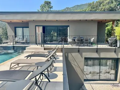 a patio with tables and chairs next to a pool at Villa neuve perchée - Vue splendide in Zonza