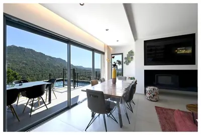 a dining room with a table and a balcony with a view at Villa neuve perchée - Vue splendide in Zonza