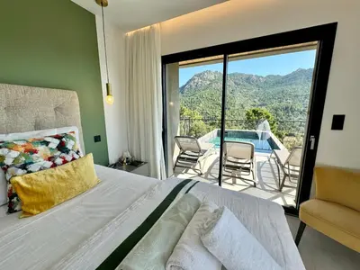 a bedroom with a bed and a balcony with a pool at Villa neuve perchée - Vue splendide in Zonza