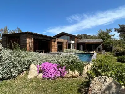 a house with a swimming pool and some flowers at Villa au bord de mer Bonifacio in Bonifacio
