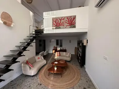 a living room with a spiral staircase and a table at Villa au bord de mer Bonifacio in Bonifacio