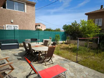 a patio with a table and chairs and a fence at Sud Bastia 50 m2 privé avec jacuzzi et piscine in Monte