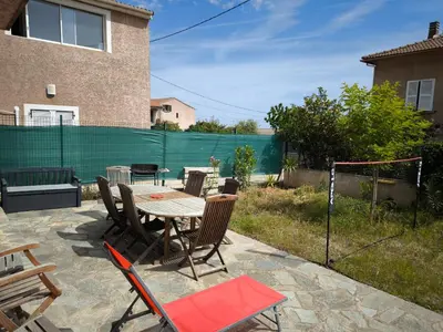 a patio with a table and chairs and a fence at Sud Bastia 50 m2 privé avec jacuzzi et piscine in Monte