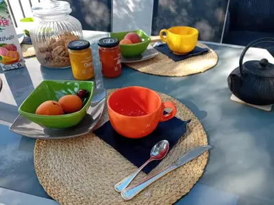 a table with bowls of fruit and cups and utensils at La maison sous les oliviers Casa d'Iloa in Porto-Vecchio