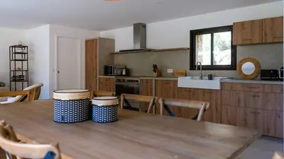 a kitchen with a wooden table with chairs and a tableasteryasteryasteryasteryastery at Domaine de Gialla Bergerie I Pini, 2 pers, piscine chauffée, 10 mn plage in Arraggio