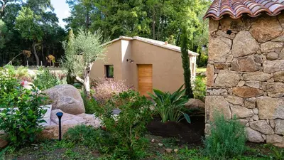 a small house in a garden with a stone wall at Domaine de Gialla Bergerie I Pini, 2 pers, piscine chauffée, 10 mn plage in Arraggio
