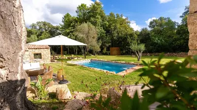 a backyard with a pool and an umbrella at Domaine de Gialla Bergerie I Pini, 2 pers, piscine chauffée, 10 mn plage in Arraggio