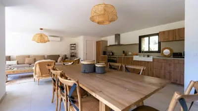 a kitchen and living room with a wooden table and chairs at Domaine de Gialla Bergerie I Pini, 2 pers, piscine chauffée, 10 mn plage in Arraggio