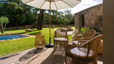 a patio with chairs and a table with an umbrella at Domaine de Gialla Bergerie I Pini, 6 pers, piscine chauffée, 10 mn plage in Arraggio