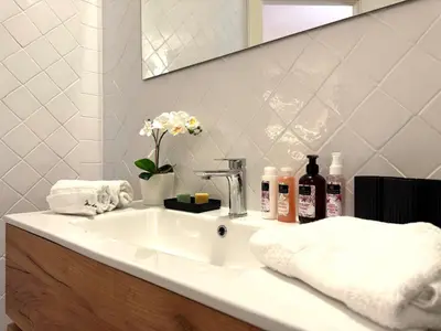 a bathroom with a sink with towels and a mirror at B&B Les Capitaineries in Bonifacio