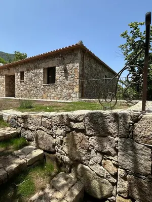 a stone wall in front of a building at Casa Scaledda in Bocognano