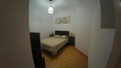 a small bedroom with a bed in a white room at Appartement Spacieux Vue Montagne- Parking gratuit- Proche ÎLE ROUSSE in Belgodère