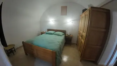 a small bedroom with a bed and a wooden cabinet at Appartement Spacieux Vue Montagne- Parking gratuit- Proche ÎLE ROUSSE in Belgodère