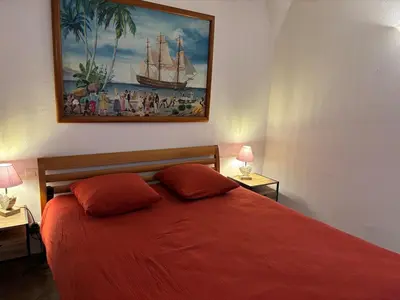 a bedroom with a red bed with a painting on the wall at Appartement Spacieux Vue Montagne- Parking gratuit- Proche ÎLE ROUSSE in Belgodère