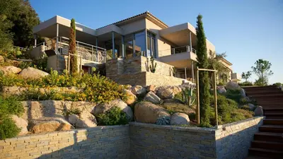 a house on a hill with a stone wall at Magnifique villa avec piscine chauffée, vue mer et montage in Porto-Vecchio