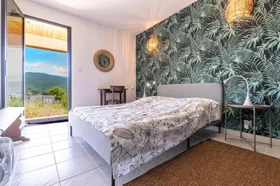 a bedroom with a bed and a large window at Casa di Ruppione - Magnifique Vue Mer in Pietrosella