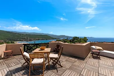 a table and chairs on a balcony with a view of the ocean at Casa di Ruppione - Magnifique Vue Mer in Pietrosella
