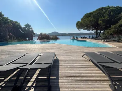a wooden deck with benches next to a swimming pool at Superbe T2 les pieds dans l'eau in Pianottoli-Caldarello