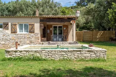 a house with a stone wall around a swimming pool at La bergerie 1 in Bonifacio