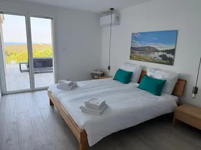 a white bedroom with a large bed with green pillows at Vacation home near Porto Vecchio in Porto-Vecchio