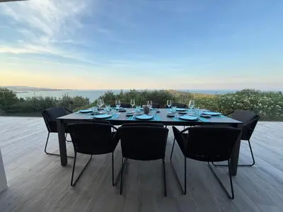 a black table with chairs and wine glasses on a deck at Vacation home near Porto Vecchio in Porto-Vecchio