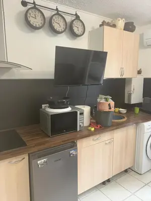 a kitchen with a microwave and clocks on the wall at Sacré cœur in Ajaccio