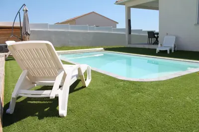 a white chair sitting next to a swimming pool at Villa Nova in Aléria
