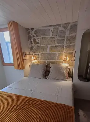 a bed in a room with a stone wall at Centre village, appartement en RDC in Sotta