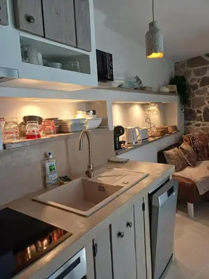 a kitchen with a sink and a living room at Centre village, appartement en RDC in Sotta