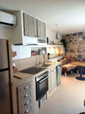 a kitchen with a stove top oven next to a living room at Centre village, appartement en RDC in Sotta