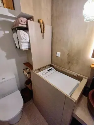 a small bathroom with a toilet and a refrigerator at Centre village, appartement en RDC in Sotta