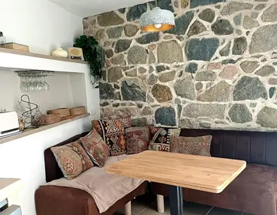 a living room with a table and a stone wall at Centre village, appartement en RDC in Sotta
