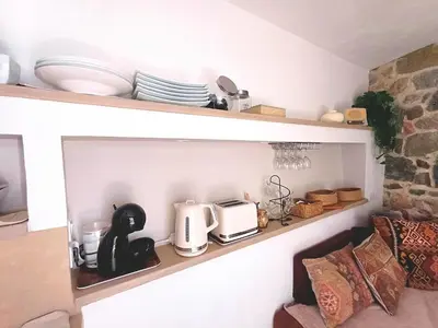 a kitchen shelf with a toaster microwave and plates at Centre village, appartement en RDC in Sotta