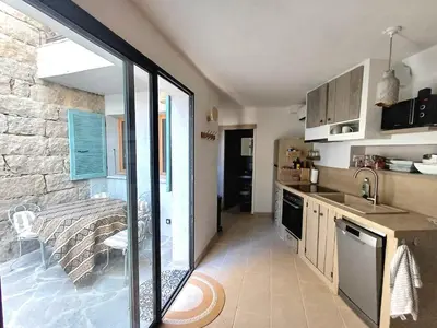 a kitchen with a stone wall and a sink and a counter at Centre village, appartement en RDC in Sotta
