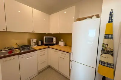 a kitchen with white cabinets and a white refrigerator at Fage - Panoramic view Spacious Luminous - by TGB in Ajaccio