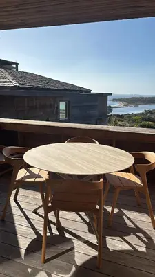 a wooden table and chairs on a deck with a view of the ocean at T2 - sea and Corsican maquis in Bonifacio