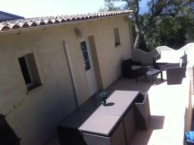 a patio with tables and chairs and a house at APPARTEMENT 2 CHAMBRES PISCINE A PARATGEr in Porto-Vecchio