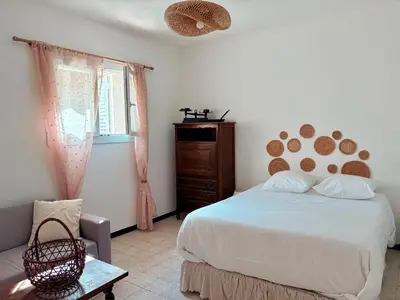 a bedroom with a bed and a chair and a window at Appartement rez de jardin - Casa San Cesaru in Bains de Guitera