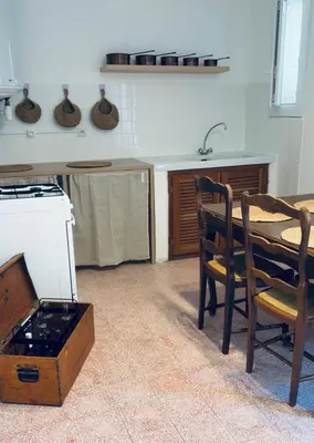 a kitchen with a table and chairs and a stove at Appartement rez de jardin - Casa San Cesaru in Bains de Guitera