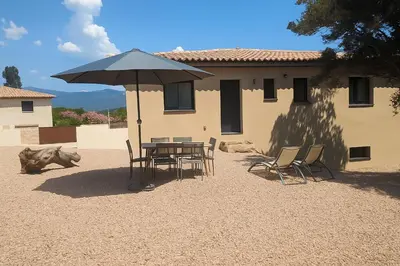 a table and chairs with an umbrella in front of a building at 2 logements a porto vecchio in Porto-Vecchio