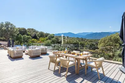 a wooden deck with a table and chairs on it at Villa Cala Serena in Zonza